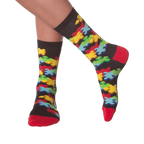 Lifestyle shot of person's legs wearing the 3D Jigsaw socks. The socks are black with colorful puzzle pieces.