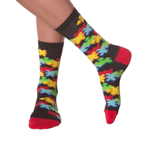 Lifestyle shot of person's legs wearing the 3D Jigsaw socks. The socks are black with colorful puzzle pieces.