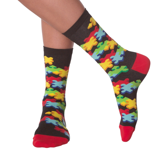 Lifestyle shot of person's legs wearing the 3D Jigsaw socks. The socks are black with colorful puzzle pieces.