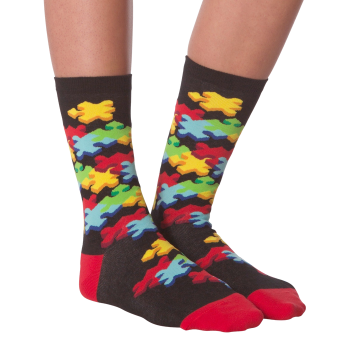 A pair of black socks with a colorful puzzle pattern. The socks have red toes and heels.