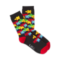 Pair of crew socks on a white background.  The socks are black with a colorful jigsaw puzzle design and red cuffs.