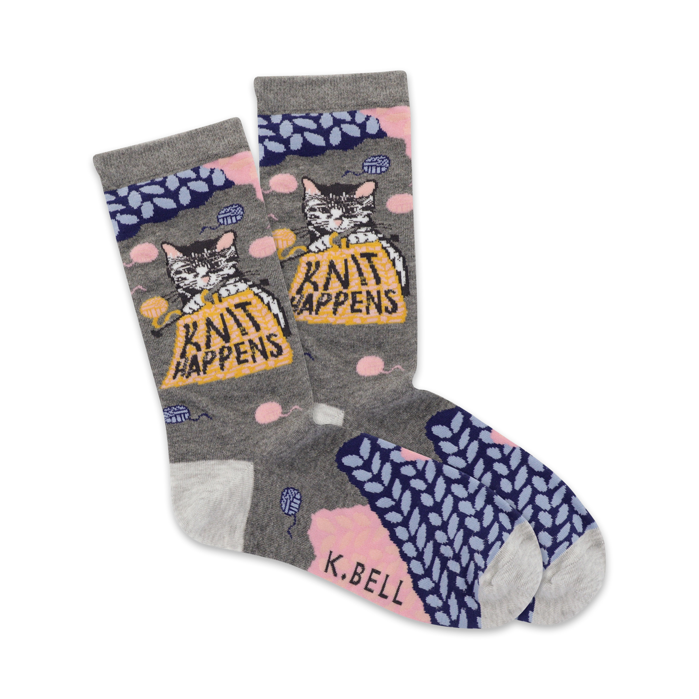A pair of grey crew socks with a cute cat knitting a ball of yarn. The socks feature pink and blue knit accents and the phrase 'Knit Happens'.