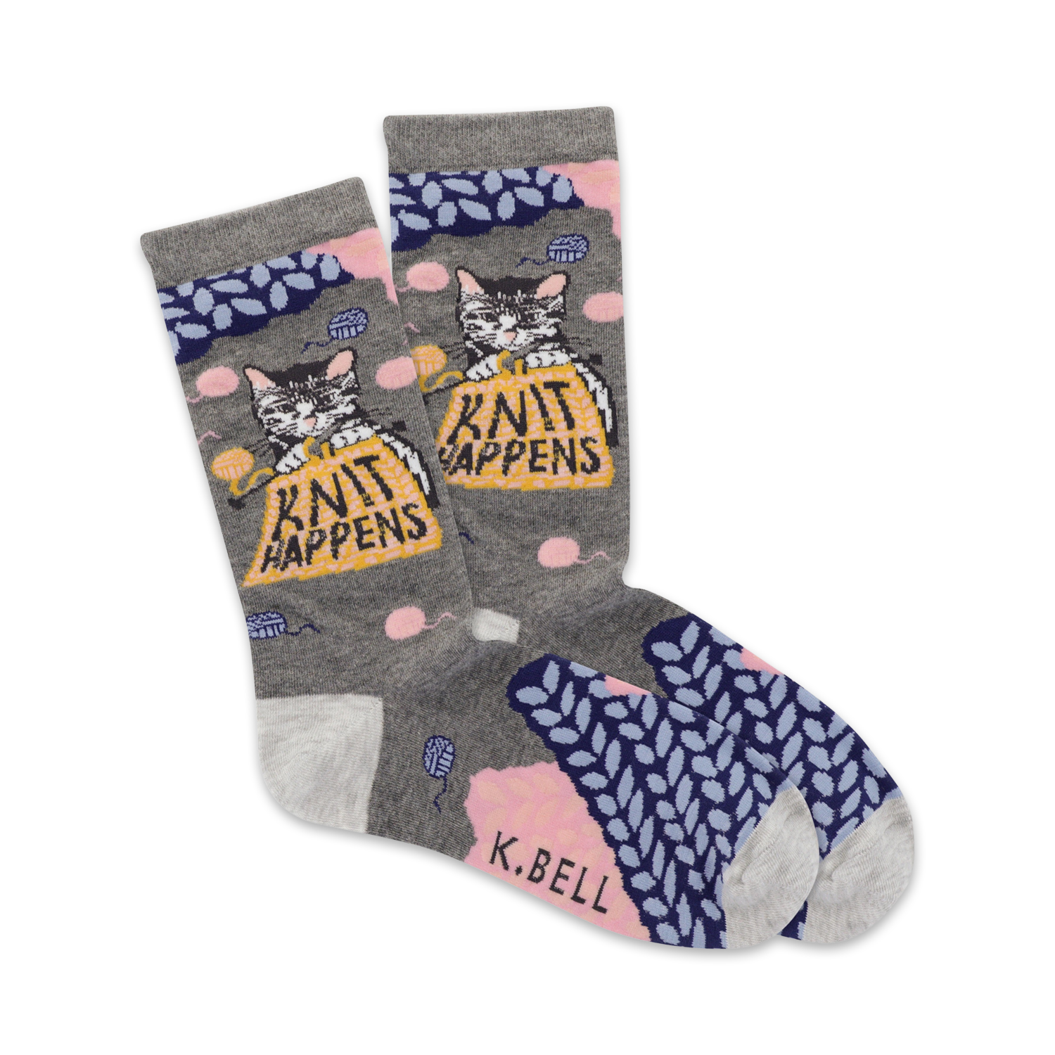 A pair of grey crew socks with a cute cat knitting a ball of yarn. The socks feature pink and blue knit accents and the phrase 'Knit Happens'.