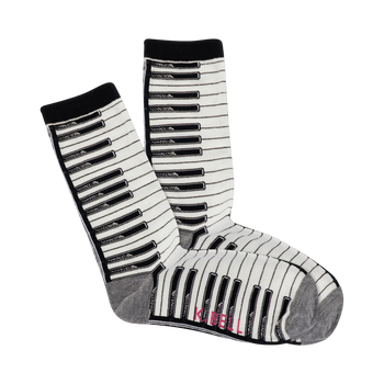 A pair of cream crew socks with a black and white piano key pattern. The cuffs are black, and the bottom is grey.