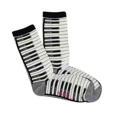 A pair of cream crew socks with a black and white piano key pattern. The cuffs are black, and the bottom is grey.