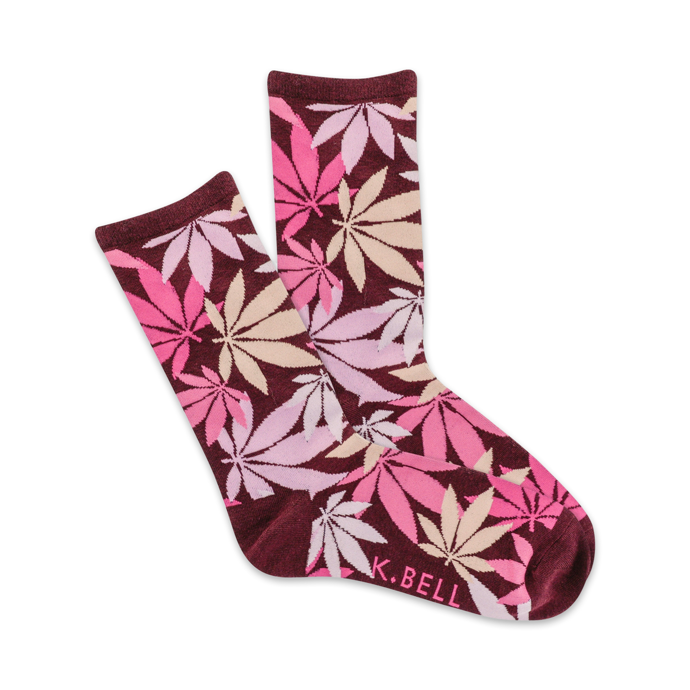 A pair of maroon crew socks with a scattered pink and beige cannabis leaf pattern. The socks are folded to show both sides of the design. K.BELL is subtly printed on one sock.