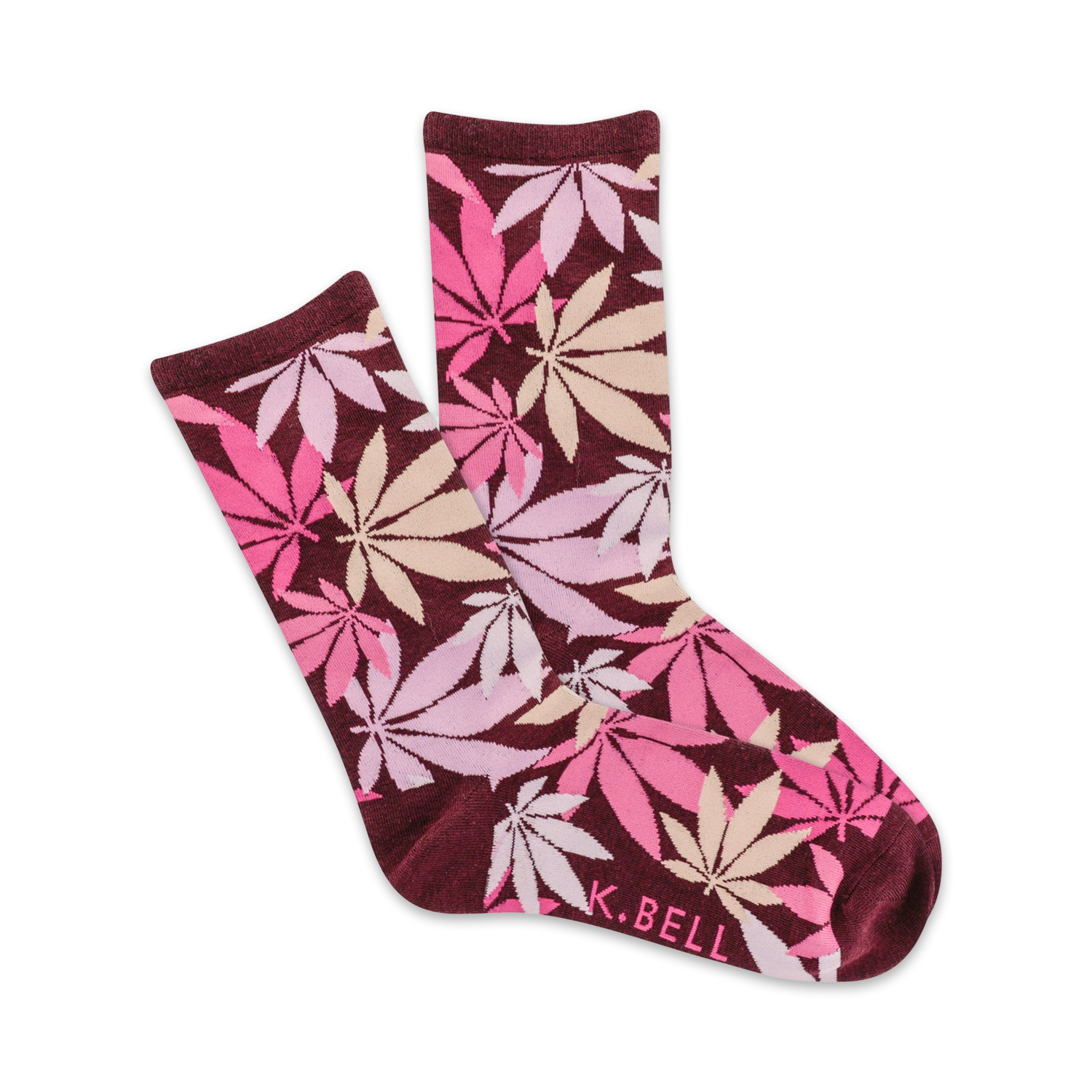 A pair of maroon crew socks with a scattered pink and beige cannabis leaf pattern. The socks are folded to show both sides of the design. K.BELL is subtly printed on one sock.