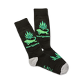 A pair of black crew socks with a fun design.  Green iguanas and marijuana leaves are featured on a black background. The socks have a grey heel and toe.