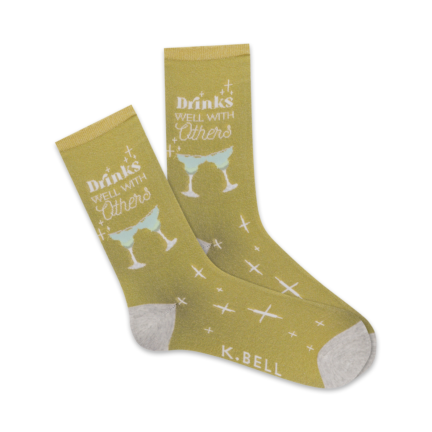Pair of crew socks in mustard yellow. Design features white text 'Drinks Well With Others' and light green margarita glasses. Small white crosses are scattered on the socks.