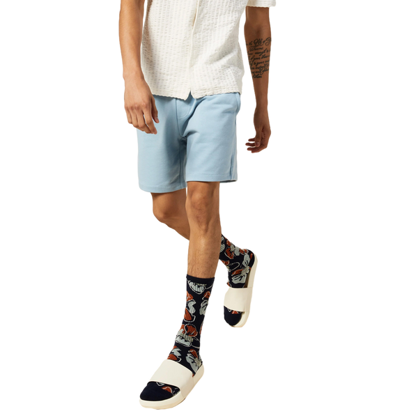 Model wearing the Tropical Floral socks with white slides and light blue shorts. [lf]