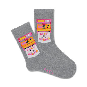 Pair of grey crew socks with a retro Polaroid camera design. The camera is yellow and pink, and the photo shows a smiling face with 'Keep Smiling' text.