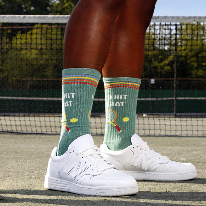 A person wearing white sneakers and green socks with the words 