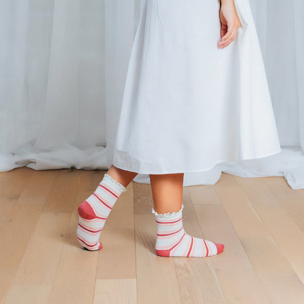 Lifestyle shot of a person wearing the dusty rose and cream striped crochet lace socks [lf]