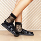 Lifestyle shot of model wearing black Net Quarter socks with black sandals. [lf]