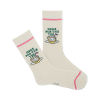 Pair of cream-colored crew socks with a pink cuff and embroidered golf-themed design: a golf ball resting in a teacup with the text 'Here For The Tee'.