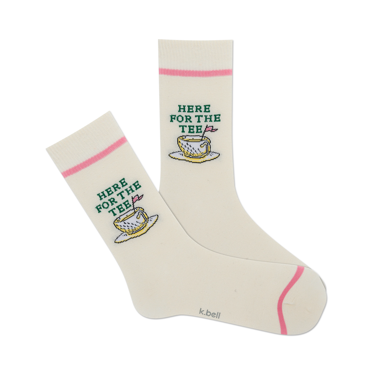 Pair of cream-colored crew socks with a pink cuff and embroidered golf-themed design: a golf ball resting in a teacup with the text 'Here For The Tee'.