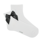 Pair of white ribbed ankle socks with a black satin bow.  The socks are shown against a black background.