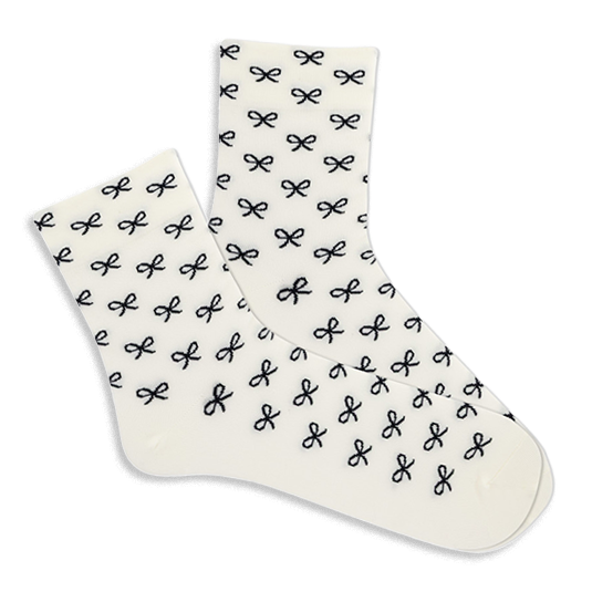 Pair of white microfiber anklet socks covered in a repeating pattern of small black bows, shown against a plain background. }}