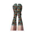 Person's legs wearing light green crew socks patterned with orange boomboxes, black records, and musical notes.