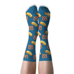A person's legs wearing blue crew socks with hot dog and pretzel pattern, shown with soles facing up against a dark background.