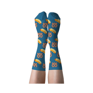 A person's legs wearing blue crew socks with hot dog and pretzel pattern, shown with soles facing up against a dark background.