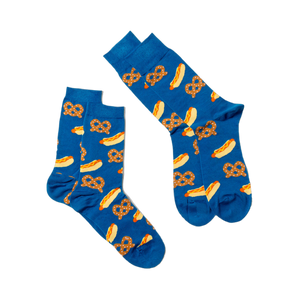 Two blue crew socks with hot dog and pretzel pattern, laid flat and angled on a white surface, one slightly overlapping.