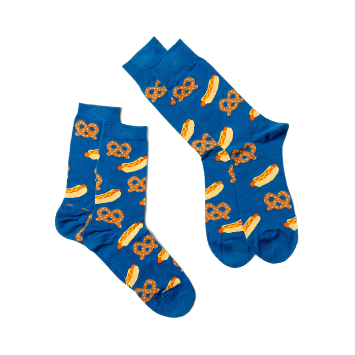 Two blue crew socks with hot dog and pretzel pattern, laid flat and angled on a white surface, one slightly overlapping.