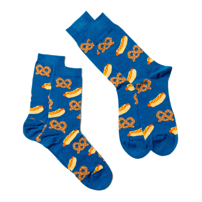 Two blue crew socks with hot dog and pretzel pattern, laid flat and angled on a white surface, one slightly overlapping.