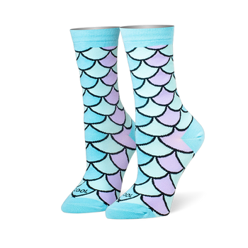 Crew socks featuring a mermaid scale pattern in pastel blue, teal, and lilac with black outlines and solid light blue cuffs.