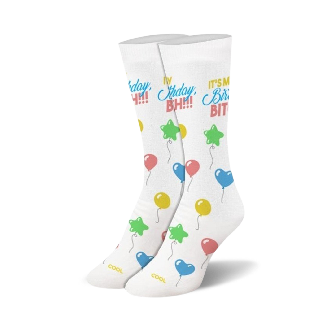 A pair of white crew socks with a 'Birthday Bitch!' slogan and colorful balloon illustrations.  Stars, hearts, and round balloons in pink, blue, yellow, and green.