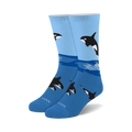 A pair of blue crew socks with a playful design featuring black and white orcas leaping from the ocean waves.