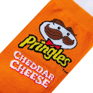 An orange sock with a white toe and white at the top. The word Pringles is written in yellow letters with a red outline. The word Cheddar is written in white letters with a black outline. The word Cheese is written in red letters with a white outline. There is a cartoon mascot of Pringles, a man with a mustache wearing a red bowtie.