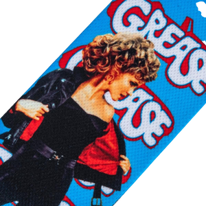 A blue background with a partial image of Sandy from the movie Grease. She is wearing a black jacket and red shirt. The word 