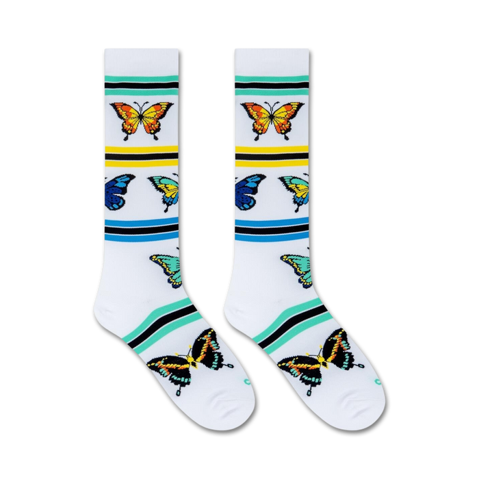 A pair of white socks with a colorful butterfly pattern and green, blue, and yellow stripes near the top.