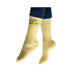 Lifestyle photo showing the yellow library card socks on a person's feet, jeans visible at the ankles.