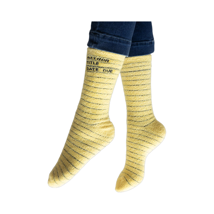 Lifestyle photo showing the yellow library card socks on a person's feet, jeans visible at the ankles.