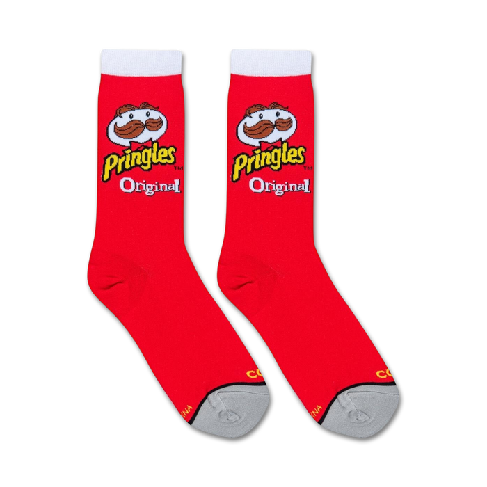 A pair of red socks with a white toe and white top. The word Pringles is written vertically in yellow letters on each sock, along with the Pringles logo, a cartoon character with a mustache. The socks are displayed on a black background with a pattern of potato chips.