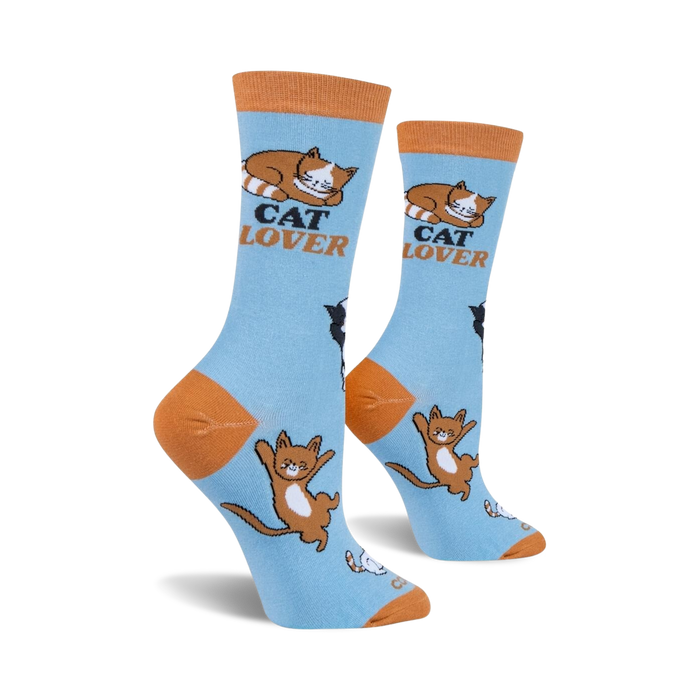 A pair of blue socks with orange toes, heels, and cuffs. The socks have a repeating pattern of cartoon cats in various poses. The words 