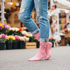 Person wearing pink striped pig face crew socks with ripped jeans at an outdoor flower market. [lf]