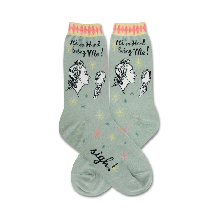 green crew socks with an illustration of a woman looking in a mirror and saying it's hard being me.  the text sigh can be seen on the foot }}