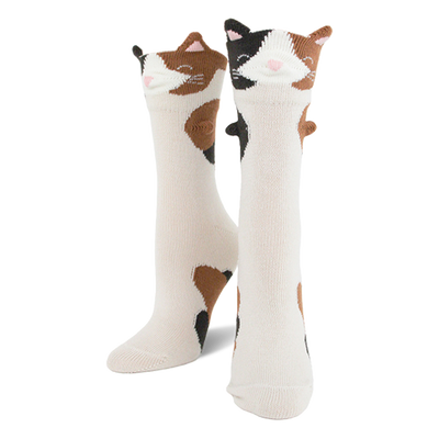 Pair of creamy white crew socks featuring calico cat faces with 3D ears and brown and black patches down the leg.