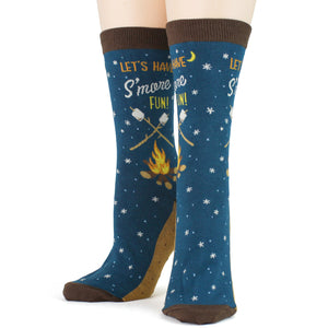 A pair of blue socks with a brown toe, heel, and cuff. The socks have a pattern of white stars and brown sticks with marshmallows roasting over a campfire. The words 