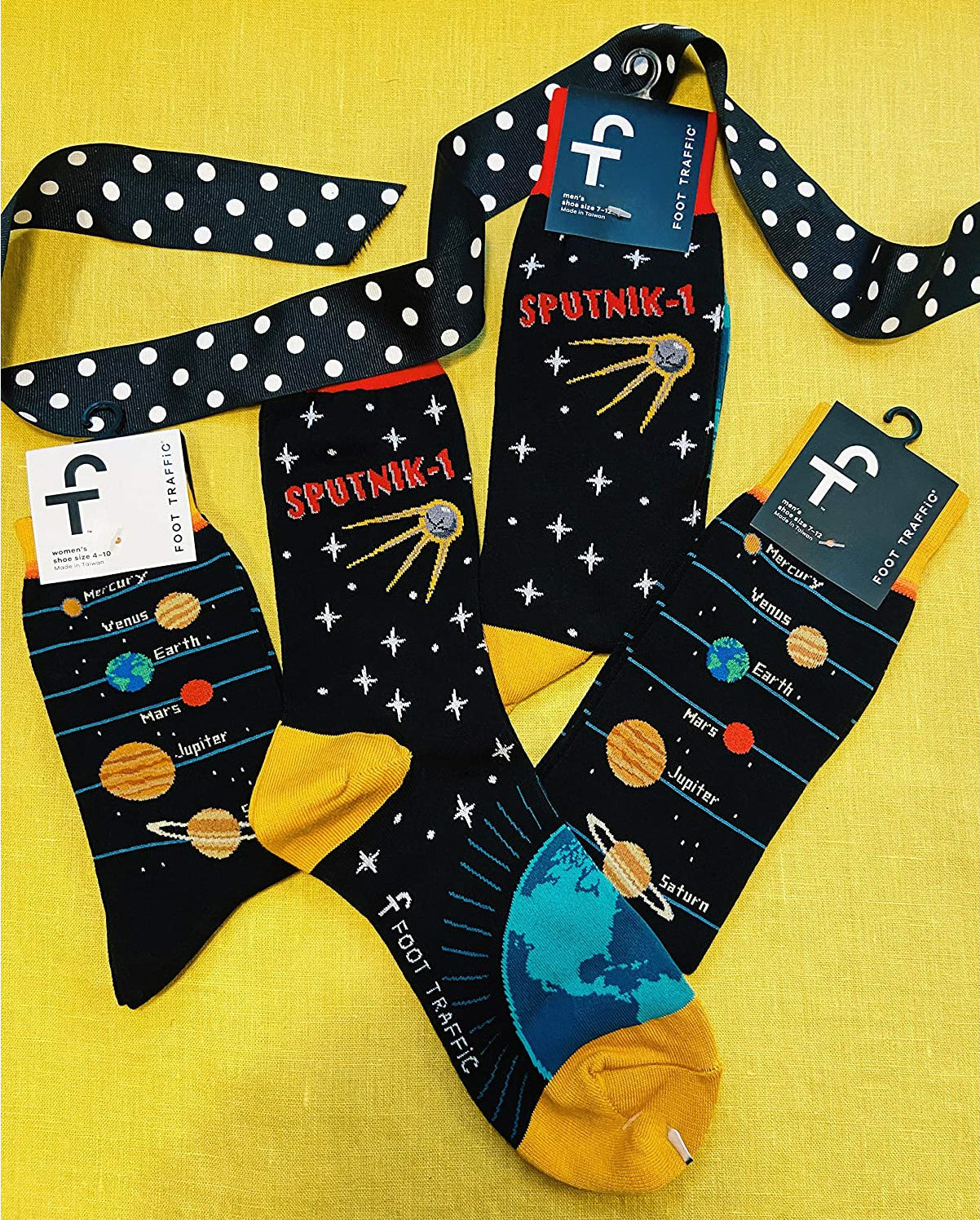 Flatlay of multiple pairs of Sputnik socks with a polka dot ribbon, showing the socks' packaging. [lf]