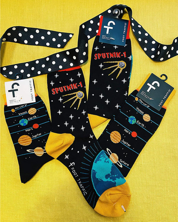 Flatlay of multiple pairs of Sputnik socks with a polka dot ribbon, showing the socks' packaging. [lf]