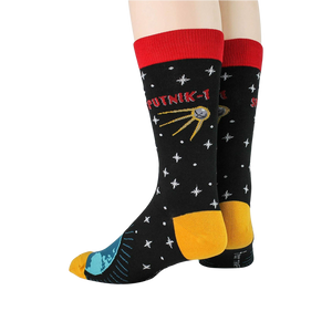 A pair of black socks with a red cuff. The socks are decorated with a pattern of white stars, a yellow and blue globe, and a red and yellow satellite. The word 