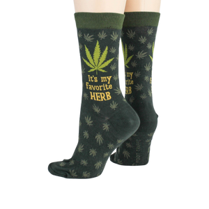 A pair of dark green crew socks with a marijuana leaf pattern and the words 