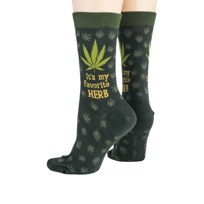 A pair of dark green crew socks with a marijuana leaf pattern and the words 