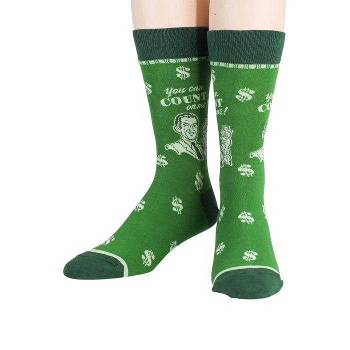 A pair of green socks with a pattern of white money symbols and a cartoon man holding a stack of money. The text on the socks reads, 