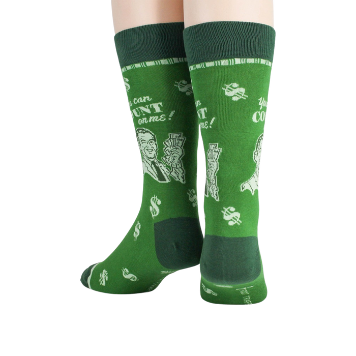 A pair of green socks with a pattern of white money symbols and a cartoon man holding a stack of money. The text on the socks reads, 