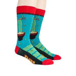 A pair of blue socks with a pattern of red chopsticks and black bowls of ramen noodles on a green background. The socks have a red top and a black heel and toe.